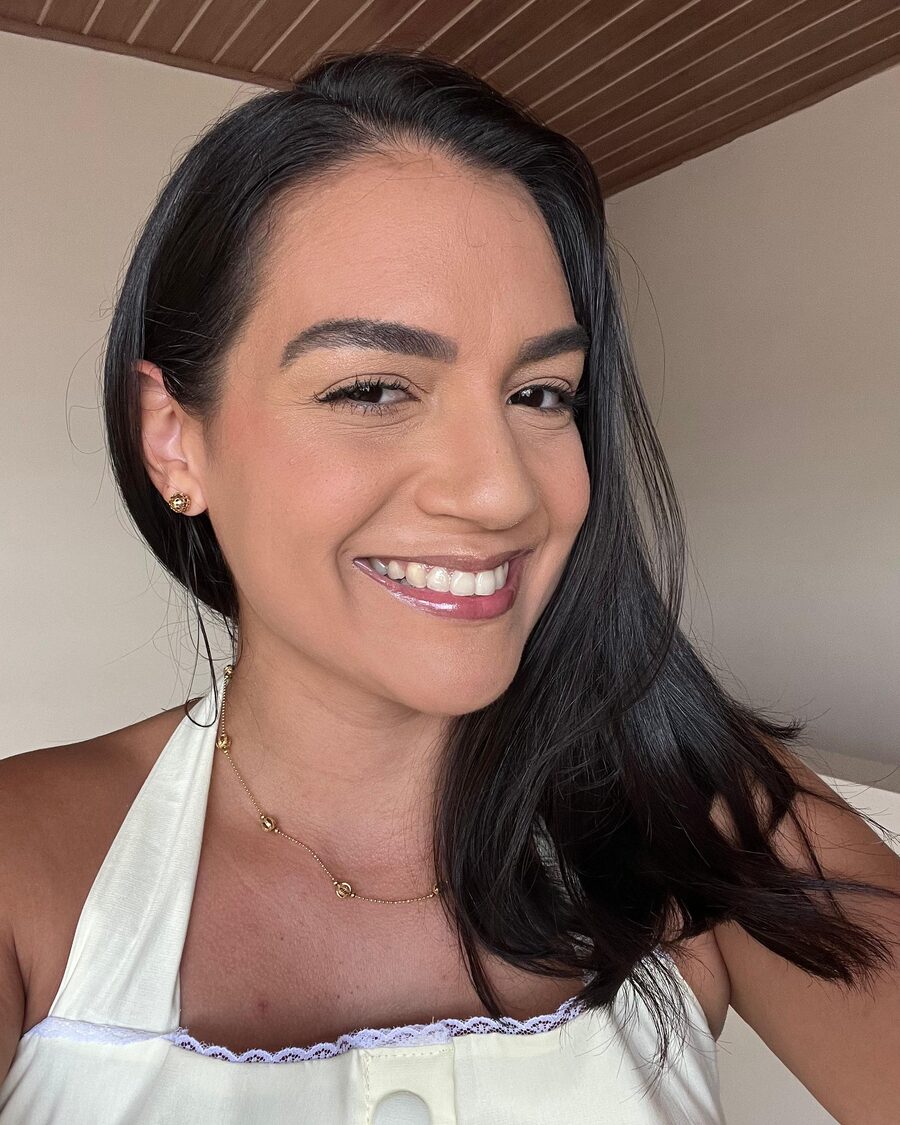 Walesca sorrindo, com cabelo preto liso e brincos dourados